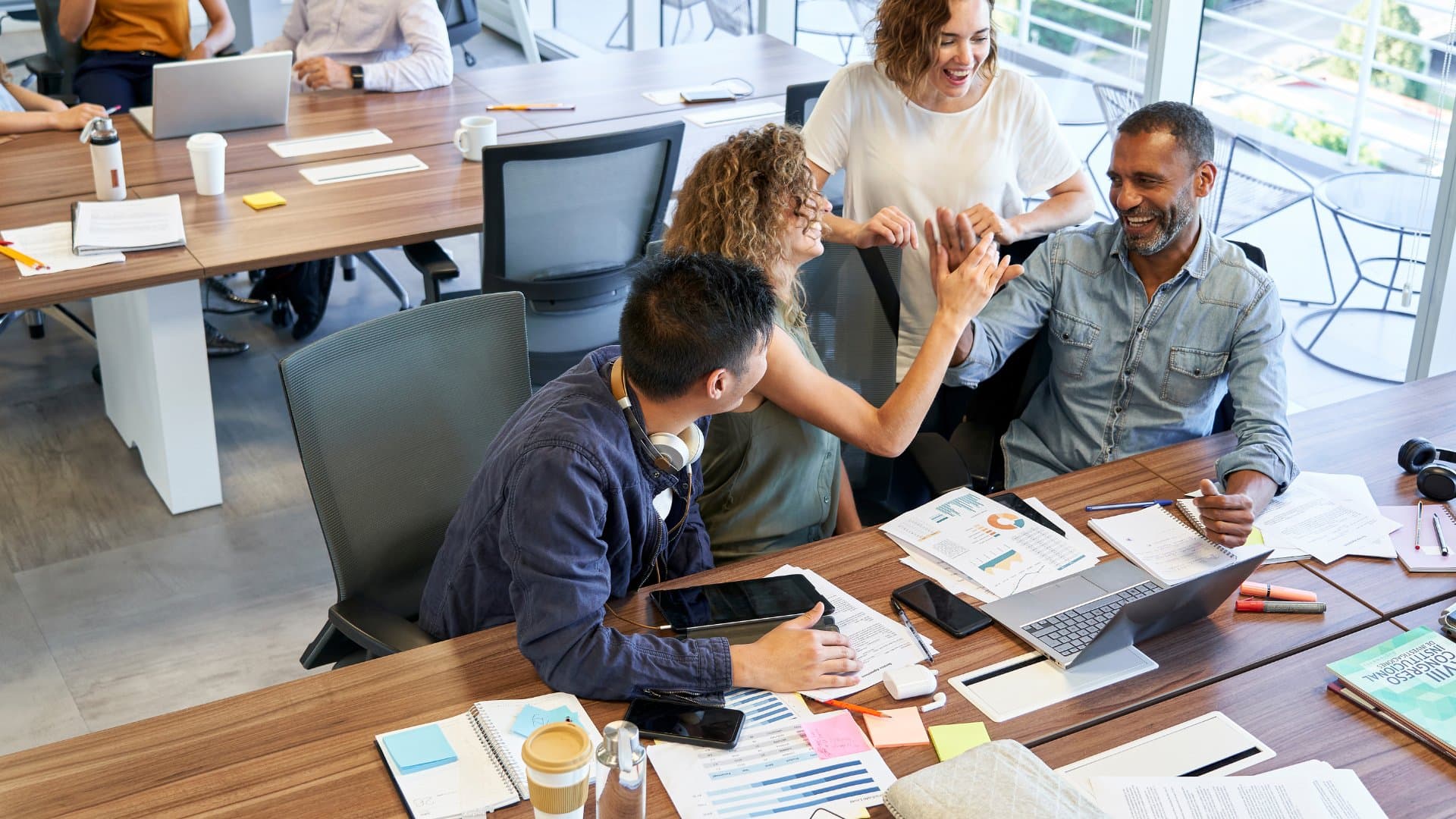 Uma equipe comemorando junto à mesa de trabalho.